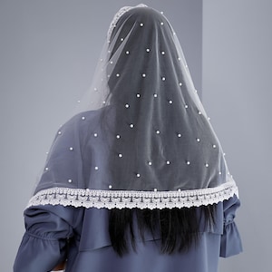 a person wearing a blue dress with a white lace trim and a white veil with small white dots.