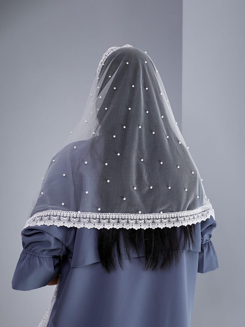 a person wearing a blue dress with a white lace trim and a white veil with small white dots.