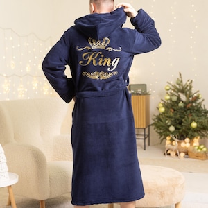 Può includere: Accappatoio blu navy con cappuccio con la scritta "King" ricamata in oro sul retro. L'accappatoio ha una cintura abbinata ed è realizzato in un materiale morbido e felpato. Un capo comodo per rilassarsi.