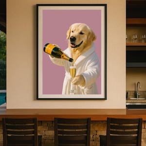 May include: Framed print featuring a Golden Retriever in a white robe pouring champagne into a glass. The dog is smiling, and the background is a solid mauve color. The champagne bottle has a black and gold label.