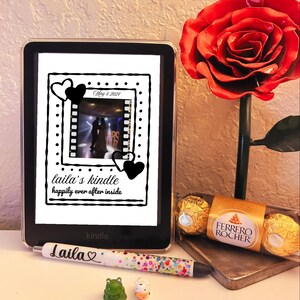 May include: A Kindle e-reader with a custom screen displaying a wedding photo and the text "laila's kindle happily ever after inside." A pen with the name "Laila" and a heart, a red rose, and chocolates are also present.