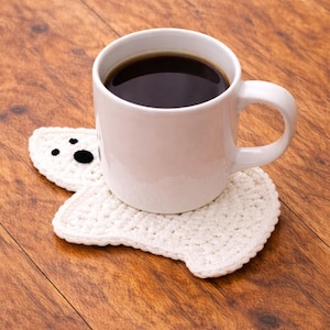 May include: A white ceramic mug with a black handle and the text "But First, Coffee" in a handwritten style. The mug is on a white surface. The mug is approximately 4 inches tall.