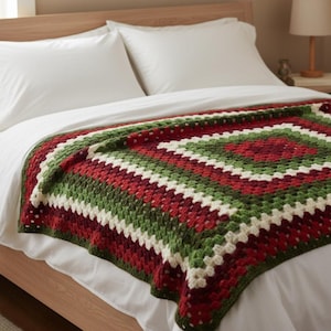 May include: A handmade, square crochet blanket in a granny square pattern. The blanket features alternating bands of red, green, and white. The blanket is displayed on a bed with white sheets and pillows.