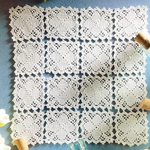 May include: White crocheted doily with a square pattern. The doily is made up of nine individual squares, each with a delicate floral design.