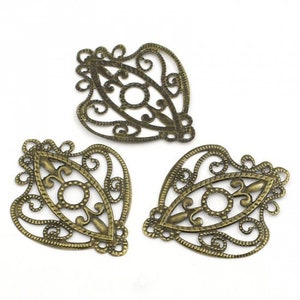 May include: Three antique gold metal filigree embellishments with a decorative eye shape in the center.