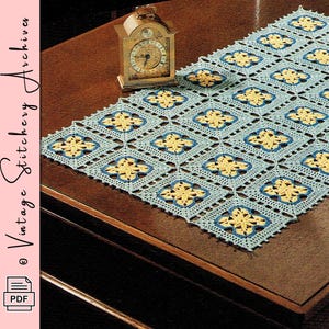 May include: A crocheted table runner featuring a repeating pattern of blue squares with yellow floral motifs. The runner is placed on a dark wooden surface, alongside a vintage clock. The text "Vintage Stitchery Archives" is visible.
