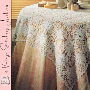 Puede incluir: Un mantel de encaje blanco tejido a ganchillo con un estampado floral cubre una mesa redonda. El mantel está drapeado sobre una mesa con un mantel de color melocotón y crema. La imagen tiene el texto "Vintage Stitchery Archives" y un icono PDF.