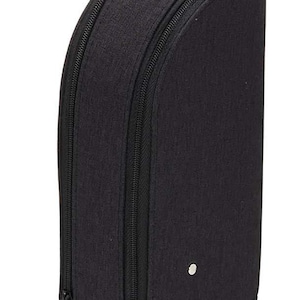 Puede incluir: Una funda de viaje negra, semicircular, con asa y cierre de cremallera. La funda tiene un asa pequeña en la parte superior y otra más grande en la parte inferior. Un pequeño botón plateado está en el lateral.