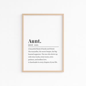 Könnte beinhalten: Ein gerahmter Druck mit der Definition von "Tante" in schwarzem Text auf weißem Hintergrund. Die Definition enthält die Aussprache und eine Beschreibung der Eigenschaften einer Tante. Der Rahmen ist hellholzfarben.