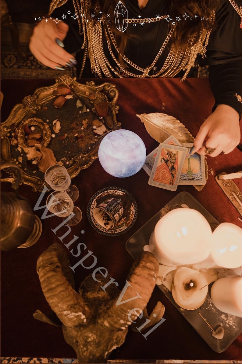Puede incluir: Una escena m&iacute;stica con una luz en forma de luna brillante, cartas del tarot, velas y una bandeja decorativa. La imagen presenta una superficie roja oscura con varios objetos asociados con la adivinaci&oacute;n y la espiritualidad. La palabra "Whisper Veil" es visible.