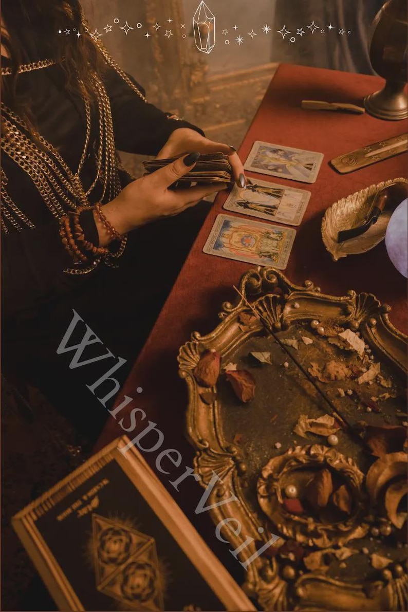 May include: A mystical scene featuring tarot cards on a red velvet table. A gold-framed tray with dried flowers and a book with geometric designs are also present. The image has a vintage aesthetic, with the text "Whisper Veil" visible.