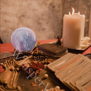 Puede incluir: Una escena m&iacute;stica con una bola de cristal brillante, cartas del tarot y una vela encendida sobre una superficie roja. La imagen tiene un ambiente c&aacute;lido y acogedor, con elementos decorativos y un tema celestial.