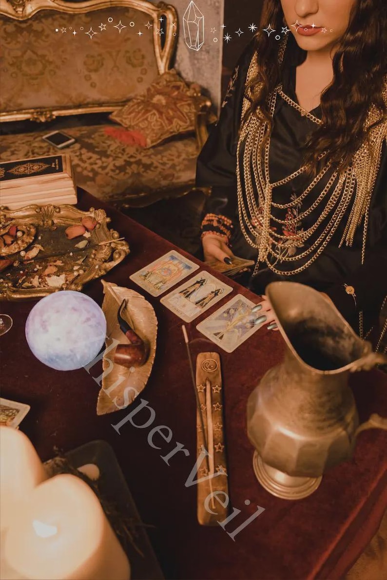 May include: A mystical scene featuring tarot cards, a crystal ball, and an incense holder on a red velvet surface. A decorative metal pitcher and a leather pipe rest on the table. The image has a vintage, bohemian aesthetic.