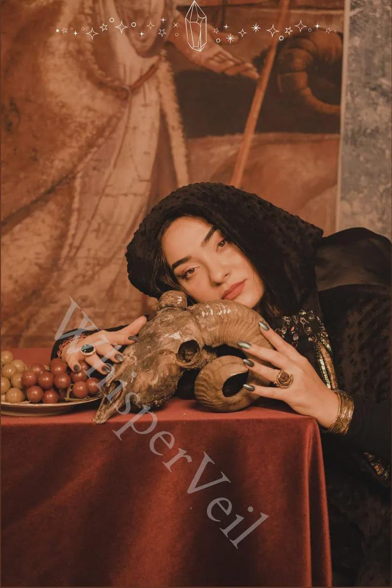 May include: A still life featuring a ram skull, grapes, and a red tablecloth. The skull is brown with curved horns. Grapes are on a white plate. The background is a sepia-toned painting.