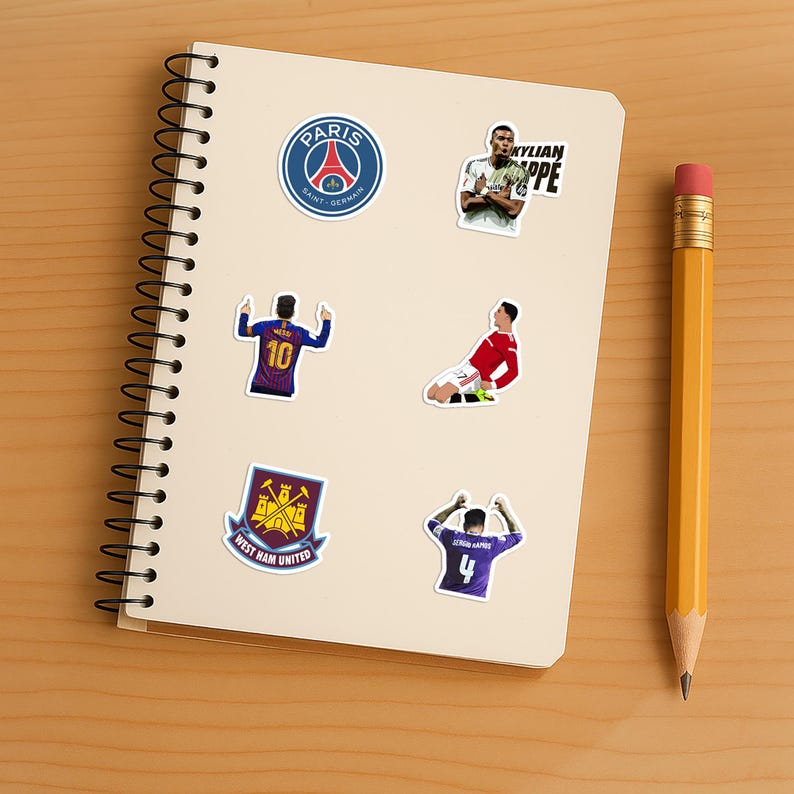 May include: A collection of colorful stickers featuring soccer players and team logos. The stickers include the Paris Saint-Germain logo, a player with the text "KYLIAN MBAPPE", and other soccer-themed designs on a white notepad.