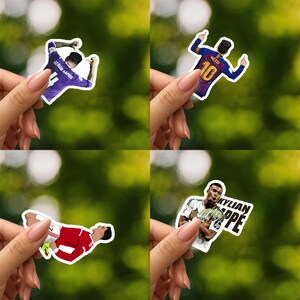 May include: Four stickers featuring soccer players in action. One sticker shows Sergio Ramos in a purple jersey, another shows Messi in a blue and maroon jersey, a third shows a player in a red jersey, and the last shows Kylian Mbappe.