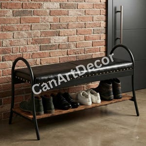 May include: A black upholstered bench with a metal frame and a lower wooden shelf for shoe storage. The seat features silver nailhead trim along the edges. The text CanArtDecor is visible across the centre of the bench seat.