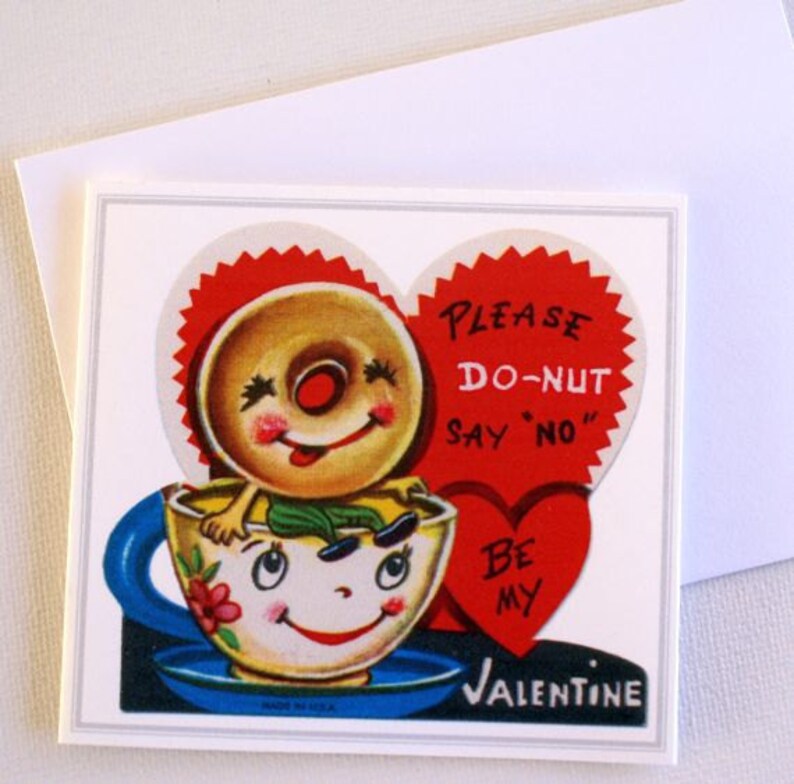 May include: A vintage Valentine's Day card with a smiling donut character in a teacup. The card has a red heart with the text "PLEASE DO-NUT SAY 'NO' BE MY VALENTINE". The teacup is yellow with a blue handle and saucer.