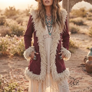 May include: A deep burgundy coat featuring long sleeves and a prominent cream-coloured faux fur trim along the front opening, collar, and cuffs. The coat is worn over a cream-coloured dress with lace detailing and layered turquoise beaded necklaces.