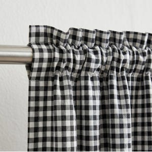 以下が含まれることがあります： シルバーのロッドに吊るされた、白と黒のギンガムチェックのカーテン。生地は上部でギャザーが寄せられ、柔らかな折り目を作っています。クラシックなパターンは、どんな部屋にも素朴な雰囲気を添えます。
