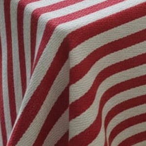 May include: Close-up of a red and white striped fabric. The stripes are thick and evenly spaced, creating a bold pattern. The fabric appears to be woven, with a slight texture visible. The color combination is classic and versatile.