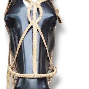 May include: A black horse head sculpture with a detailed tan bridle. The bridle features woven rope and leather straps, with metal hardware. The sculpture is a decorative item, likely for equestrian enthusiasts or home decor.
