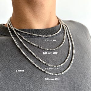 Può includere: Una persona indossa una collana a catena d'argento. L'immagine mostra tre collane a catena d'argento di diverse lunghezze: 45 cm (18 pollici), 50 cm (20 pollici), 55 cm (22 pollici) e 60 cm (24 pollici). La catena è spessa 3 mm.