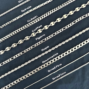 Può includere: Una collezione di collane a catena color argento in vari stili, tra cui box, spirale, cubain, chicco di caffè, figaro, corda, gourmette, small fine e small box. Ogni catena è presentata su uno sfondo scuro.