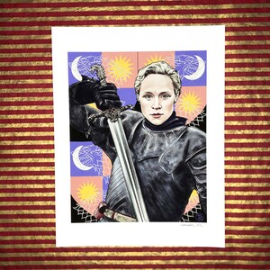 May include: A digital illustration of a woman in armor holding a sword. The background is a colorful pattern of stars, moons, and wolves. The woman has short blonde hair and is wearing a black and silver suit of armor. The sword is silver with a black hilt.