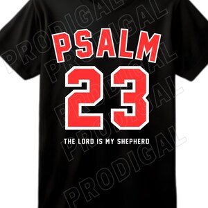Może przedstawiać: Czarna koszulka z napisem "PSALM 23" w czerwonych, blokowych literach z białym obrysem. Poniżej cyfr znajduje się napis "THE LORD IS MY SHEPHERD" w kolorze białym. Koszulka ma okrągły dekolt.