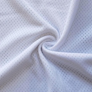 May include: Close-up of white athletic mesh fabric with small, evenly spaced holes. The fabric is gathered and swirled, creating soft folds and shadows. The material appears lightweight and breathable.