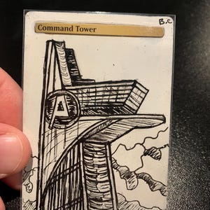 May include: A rectangular trading card featuring a black ink hand-drawn illustration of a tall tower with a circular emblem containing the letter A. The text Command Tower is printed in a gold bar at the top, with the initials B.C in the corner.