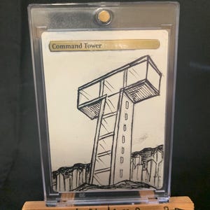 May include: A black and white sketch of a command tower, displayed in a clear protective case. The artwork is mounted on a small wooden easel with the text "Weerd Studios 3" printed on the front.