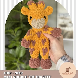 May include: A handmade crochet giraffe toy in shades of yellow, brown, and beige. The giraffe has a textured, plush appearance with brown spots and accents. The text "LOW - SEW MINI NOODLE THE GIRAFFE DIGITAL DOWNLOAD CROCHET PATTERN" is visible.