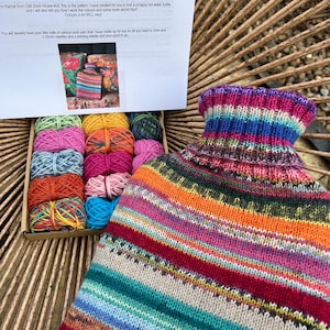 May include: A colourful scrappy sock pattern kit for knitting a hot water bottle. The kit includes a variety of yarn colours and a printed instruction sheet with the title "Scrappy Sock Pattern".
