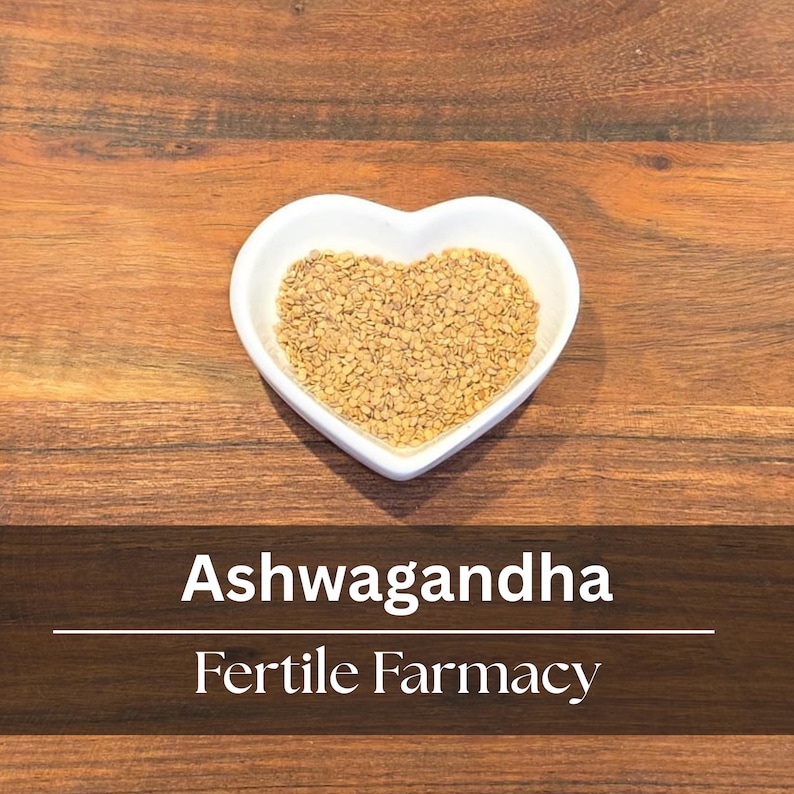 May include: A white heart-shaped bowl filled with small, tan seeds, set against a dark wooden surface. The text "Ashwagandha" and "Fertile Farmacy" are displayed below the bowl.