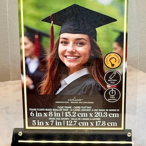 May include: Clear acrylic graduation photo frame with a black base. The frame holds a 6 x 8 inch photo (15.2 cm x 20.3 cm) and the image size shown is 5 x 7 inches (12.7 cm x 17.8 cm).