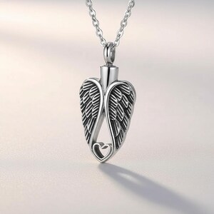 Può includere: Collana con pendente argentato a forma di ali d'angelo con un ritaglio a forma di cuore. Il pendente è appeso a una delicata catena. Le ali presentano dettagli di piume incise.