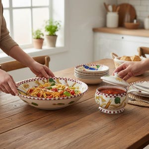 May include: A ceramic serving bowl filled with pasta, tomatoes, and herbs, alongside a matching lidded sauce pot with a handle. Both pieces feature a cream base, a red and white checkered rim, and colorful illustrations of various pasta shapes.