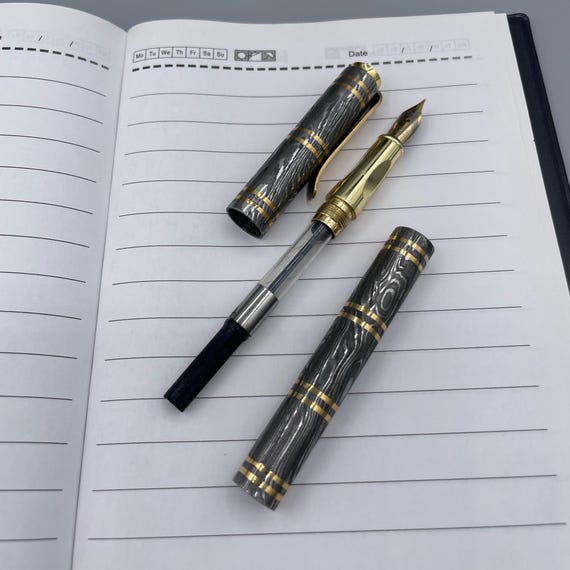 A fountain pen forged from Damascus steel is genuinely unexpected — the wavy layered-steel aesthetic on a writing instrument is a conversation stopper on any desk.