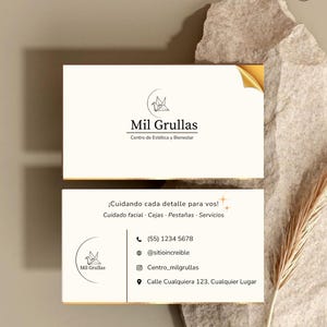 Puede incluir: Tarjeta de visita para "Mil Grullas", un centro de estética y bienestar. La tarjeta presenta el nombre y el logotipo de la empresa, junto con información de contacto, como un número de teléfono, un identificador de Instagram y una dirección. El diseño es limpio y moderno, con un acento de esquina dorada.