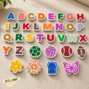 May include: A collection of colourful, three-dimensional plastic alphabet letters from A to Z, alongside various shapes including a football, volleyball, baseball, rugby ball, two flowers, a backpack, and a butterfly. Text reads STL,3MF.