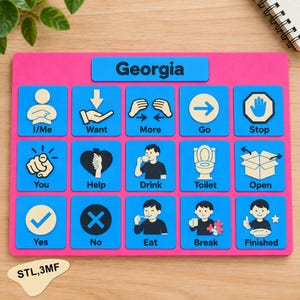 Può includere: Una tavola di comunicazione rettangolare rosa con il nome Georgia stampato in alto. Presenta quindici icone quadrate blu con testo nero e illustrazioni che rappresentano concetti come I/Me, Want, More, Go, Stop, You, Help, Drink, Toilet, Open, Yes, No, Eat, Break e Finished.