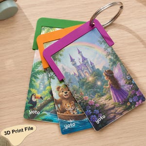 Puede incluir: Tres tarjetas rectangulares Yoto unidas por una anilla metálica. La tarjeta superior muestra un hada con vestido morado cerca de un castillo y un arcoíris. La tarjeta central muestra un oso y un tigre en un bote. La tarjeta inferior muestra un tucán en la selva.