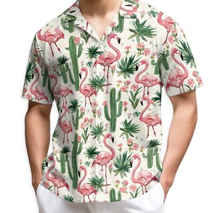 May include: Short-sleeved button-down shirt with a cream background, featuring a repeating pattern of pink flamingos, green cacti, and tropical flowers. The shirt has a classic collar and a relaxed fit.