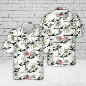 May include: White short-sleeved shirt with a tropical pattern. The design includes aeroplanes, palm trees, and hibiscus flowers in black, green, red, and blue. The shirt has a classic collar and a relaxed fit.