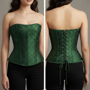 Puede incluir: Un corsé verde esmeralda sin tirantes con un estampado floral. El corsé tiene un corpiño estructurado y una espalda con cordones. La tela tiene un brillo sutil y los bordes están ribeteados con un ribete verde más oscuro.