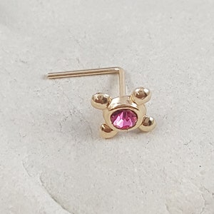 以下が含まれることがあります： 中心にピンクのクリスタル、周りに4つのゴールドボールが付いたゴールドの鼻のリング