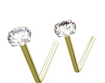 May include: Two gold nose rings with clear round cubic zirconia stones. The rings are L-shaped and have a smooth finish.