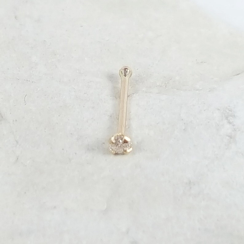 May include: A gold nose ring with a small, clear diamond.